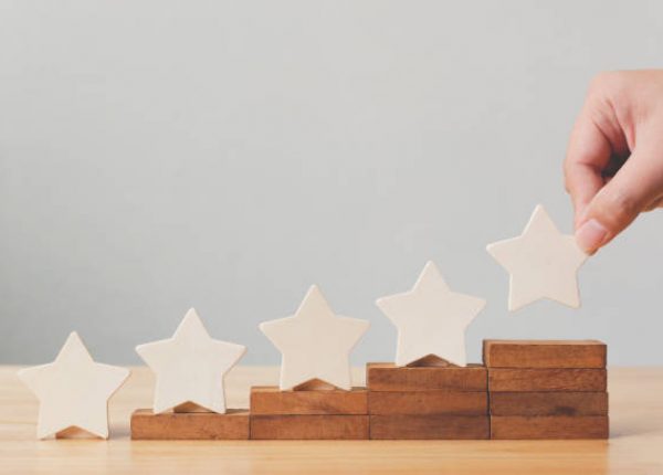 Hand putting wooden five star shape on table. The best excellent business services rating customer experience concept